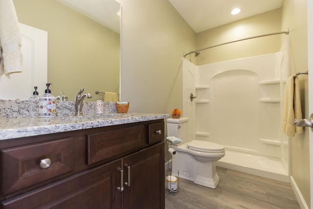 full bathroom with wood finished floors, toilet, vanity, baseboards, and a stall shower