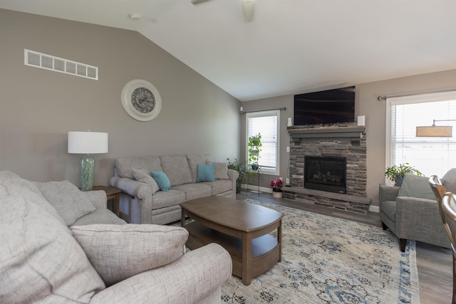 living area with lofted ceiling, wood finished floors, visible vents, a fireplace, and ceiling fan