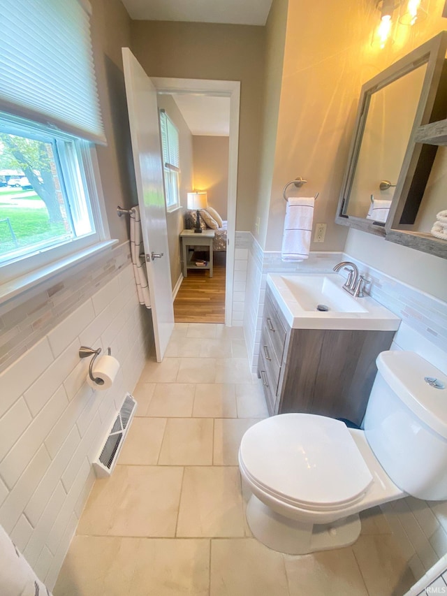 4405 Parkwood Dr, Kokomo, IN 46901 - bathroom with toilet, tile patterned flooring, vanity, tile walls, and a wainscoted wall