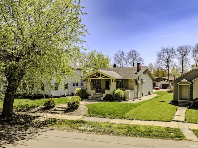 bungalow-style house featuring a chimney and a front yard