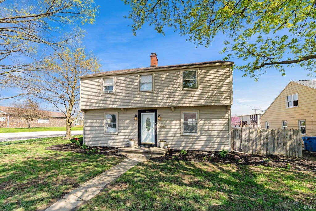 back of property with fence, a yard, and a chimney