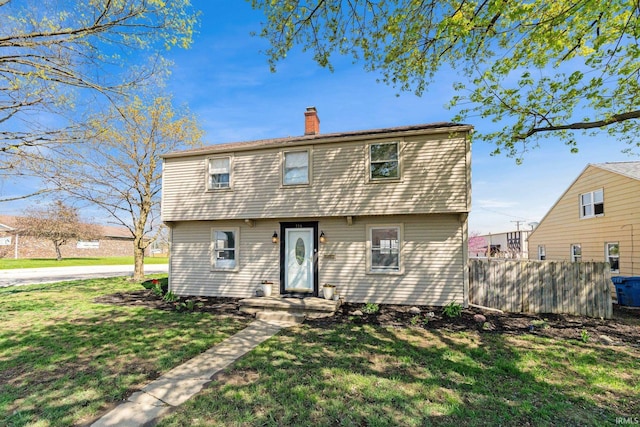 back of property with fence, a yard, and a chimney