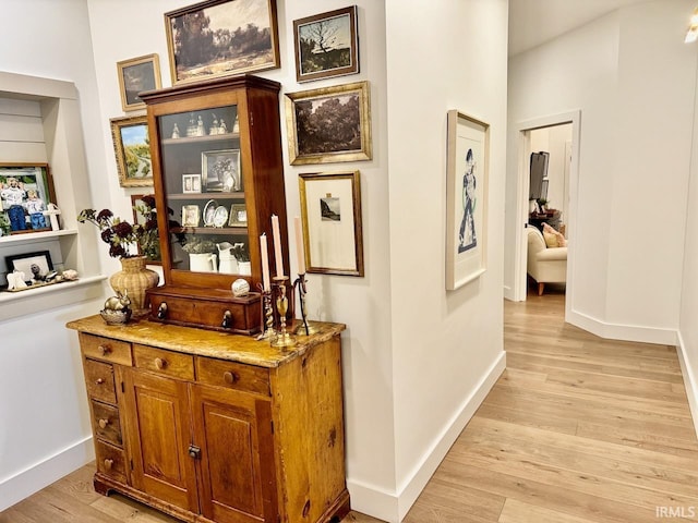 hall with light wood-style flooring and baseboards
