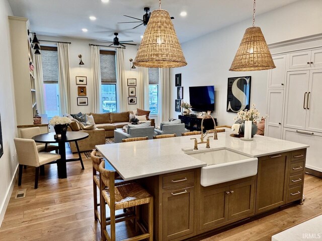 kitchen featuring open floor plan, ceiling fan, visible vents, and a sink