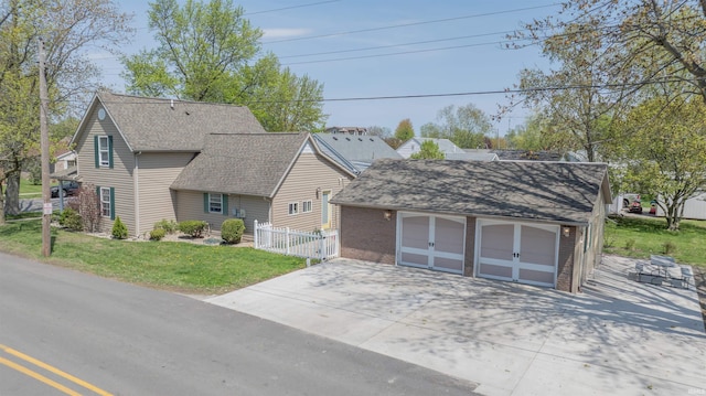 view of front of home with fence, a shingled roof, a front lawn, a detached garage, and an outdoor structure