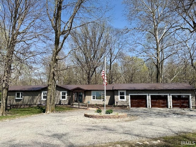 single story home with stone siding, a garage, and aphalt driveway