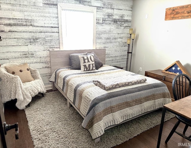 bedroom with wood walls, wood finished floors, and an accent wall