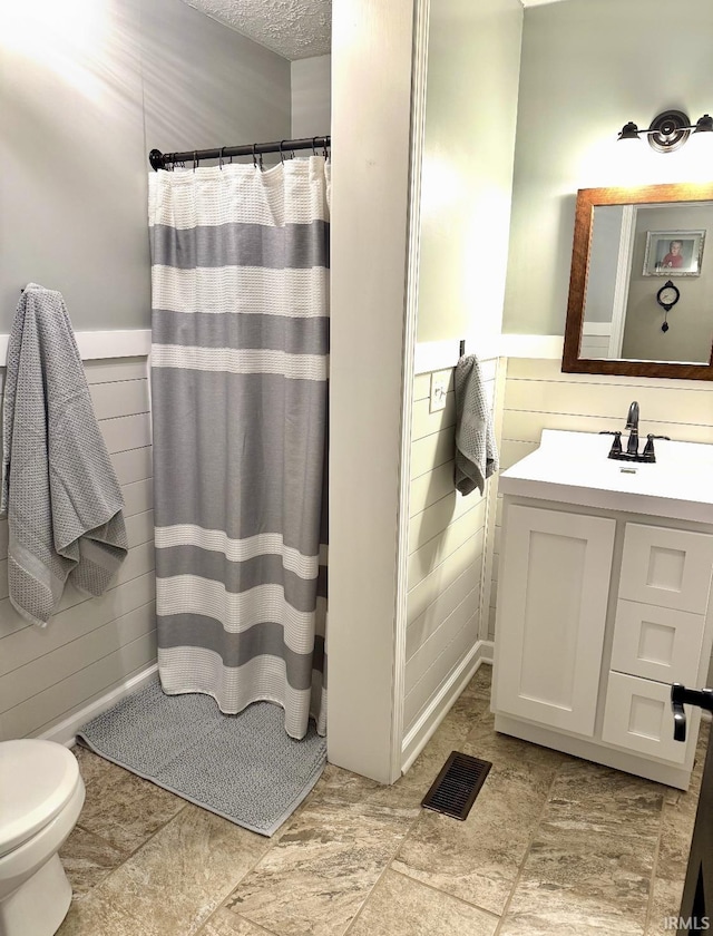 bathroom with wainscoting, wood walls, a shower with shower curtain, vanity, and visible vents