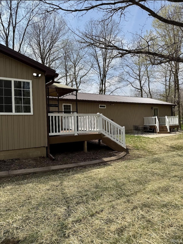 back of property with a lawn, board and batten siding, and a wooden deck