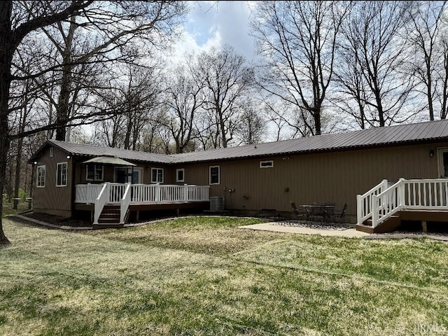 rear view of property featuring metal roof, a wooden deck, a yard, and central AC unit