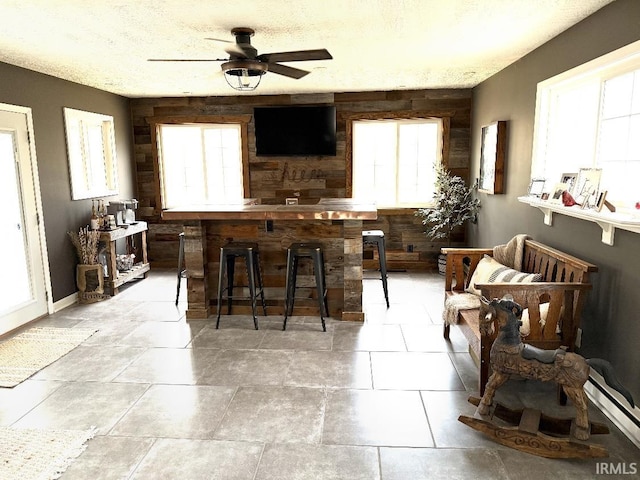kitchen featuring a textured ceiling, plenty of natural light, a ceiling fan, and a baseboard heating unit