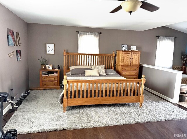 bedroom featuring baseboards, wood finished floors, ceiling fan, and multiple windows