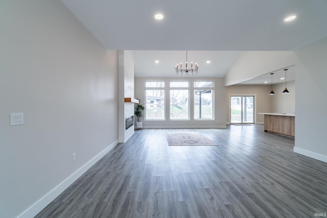 619 Sandringham Pass, Fort Wayne, IN 46845 - unfurnished living room with lofted ceiling, a chandelier, baseboards, a fireplace, and wood finished floors