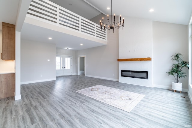 619 Sandringham Pass, Fort Wayne, IN 46845 - unfurnished living room featuring baseboards, wood finished floors, an inviting chandelier, and a glass covered fireplace