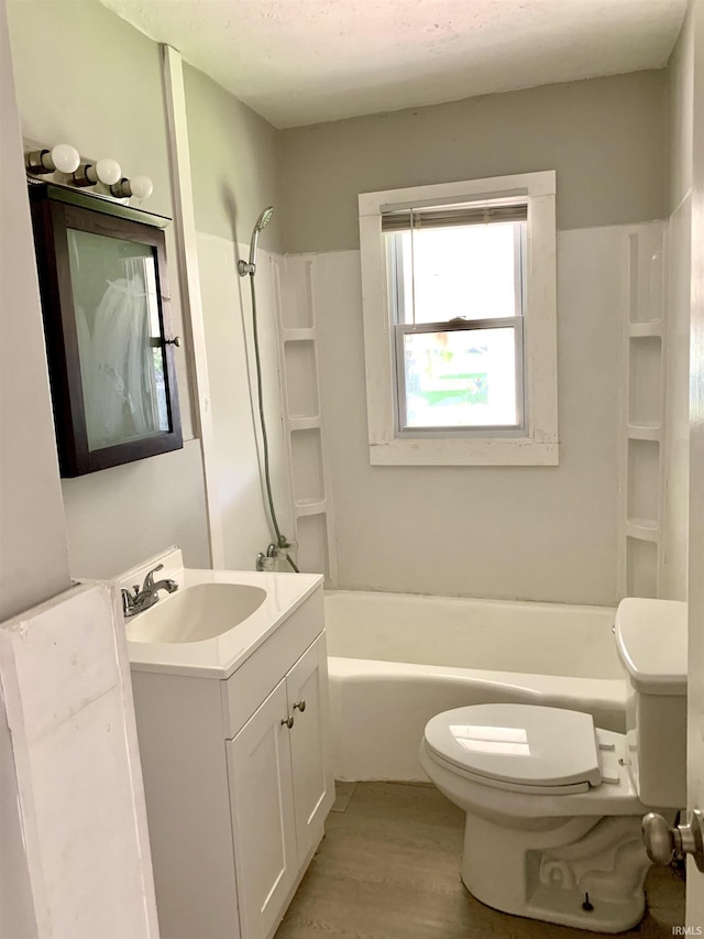 bathroom with toilet, vanity, tub / shower combination, and wood finished floors