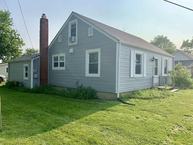 view of side of home with a chimney, a shingled roof, cooling unit, and a lawn
