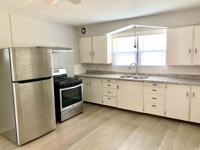 kitchen featuring appliances with stainless steel finishes, light wood-style floors, tasteful backsplash, and a sink