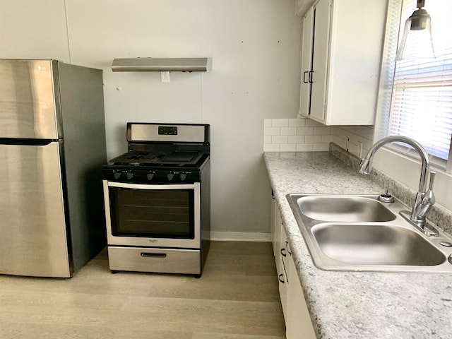 kitchen featuring white cabinets, a sink, stainless steel appliances, light countertops, and light wood-type flooring
