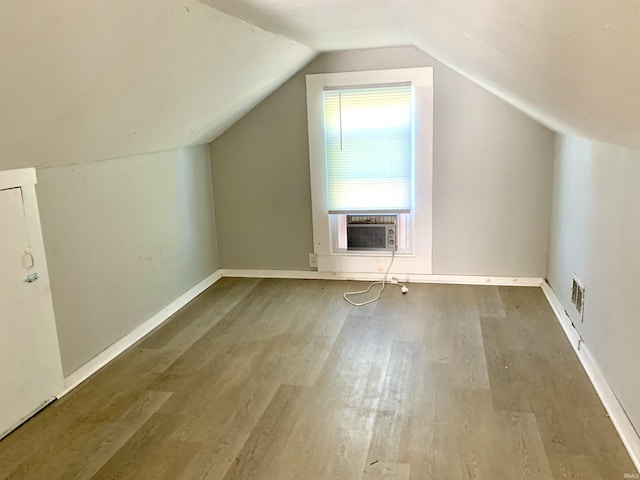 bonus room featuring wood finished floors, cooling unit, baseboards, visible vents, and lofted ceiling