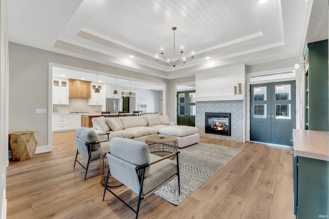 1152 Cascata Trl, Huntertown, IN 46748 - living room featuring a glass covered fireplace, an inviting chandelier, light wood-style flooring, and a tray ceiling