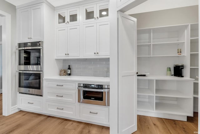 1152 Cascata Trl, Huntertown, IN 46748 - kitchen with light wood-style flooring, double oven, open shelves, and white cabinetry