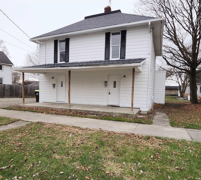 view of front of home with a chimney, fence, covered porch, and roof with shingles