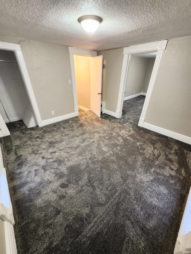 interior space with a textured ceiling, baseboards, and carpet floors