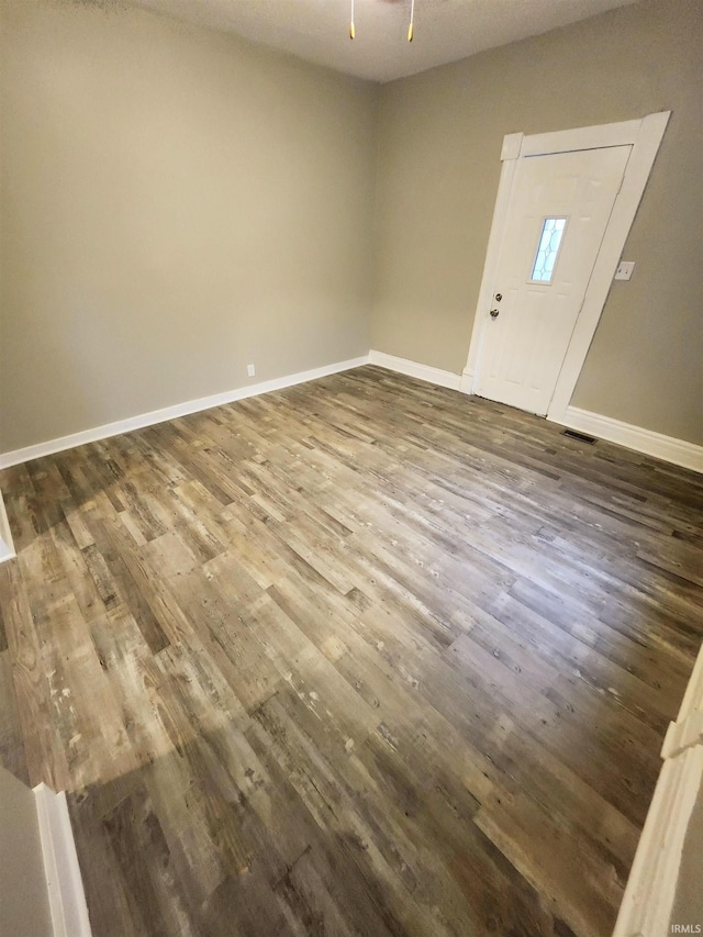 unfurnished room with dark wood-type flooring, ceiling fan, visible vents, and baseboards