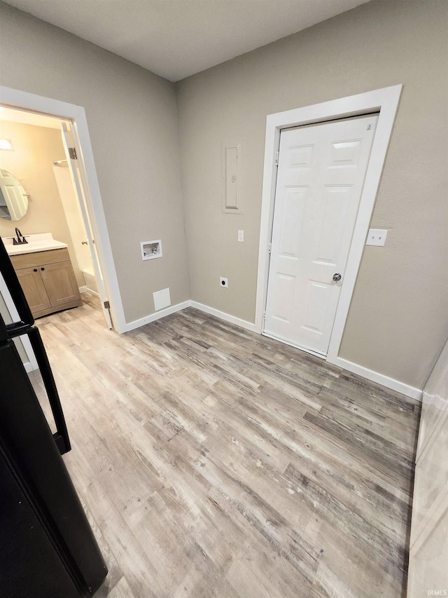 laundry area with baseboards, light wood-type flooring, and laundry area