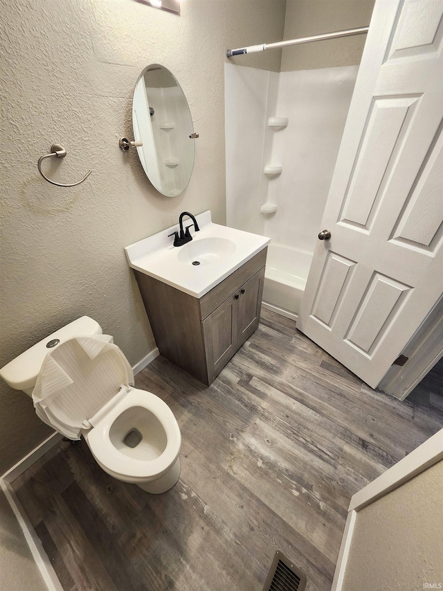 full bath featuring vanity, shower / bath combination, toilet, visible vents, and wood finished floors