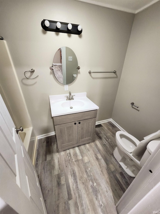 bathroom with wood finished floors, vanity, toilet, and baseboards