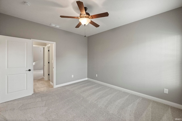 spare room with baseboards, ceiling fan, and light colored carpet