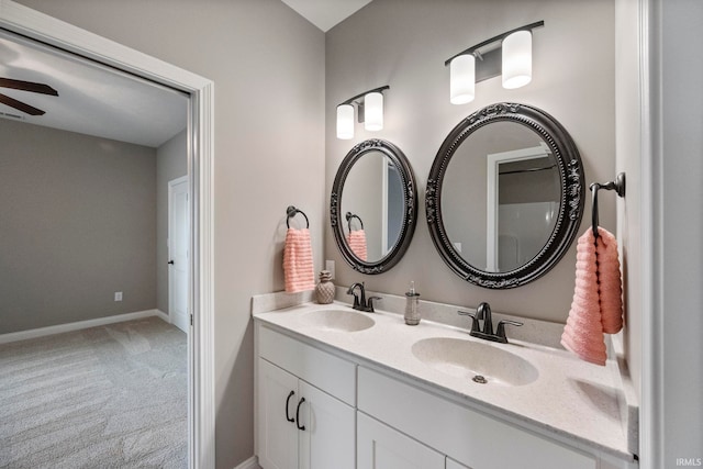bathroom with double vanity, a sink, a ceiling fan, and baseboards