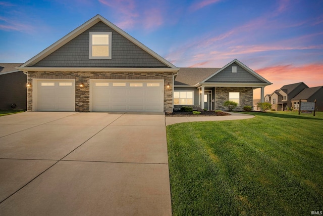 view of front of house with a lawn, stone siding, an attached garage, and concrete driveway
