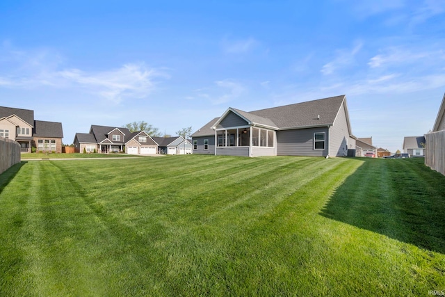 rear view of house featuring a yard, a residential view, and a sunroom
