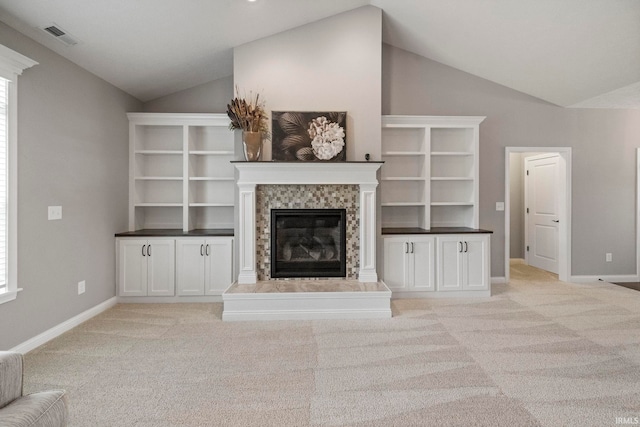 unfurnished living room featuring a tile fireplace, visible vents, vaulted ceiling, baseboards, and light colored carpet