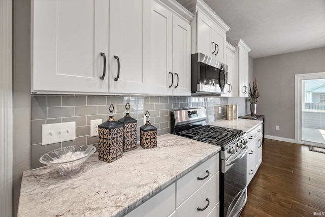 kitchen with dark wood-style flooring, light stone counters, baseboards, white cabinets, and appliances with stainless steel finishes