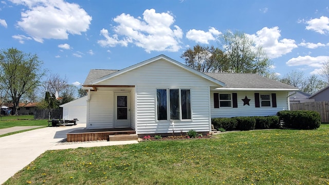 view of front of property featuring a detached garage, a front yard, roof with shingles, and fence