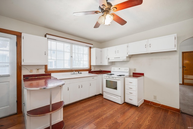 kitchen with white cabinetry, a sink, under cabinet range hood, white electric range, and wood finished floors