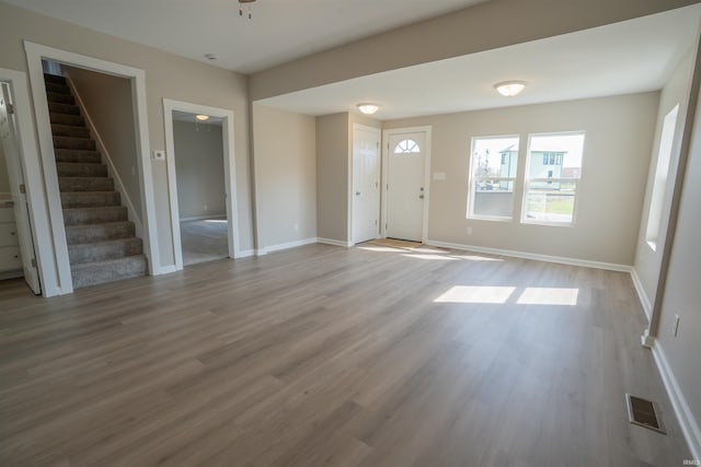 entrance foyer featuring visible vents, stairway, wood finished floors, and baseboards