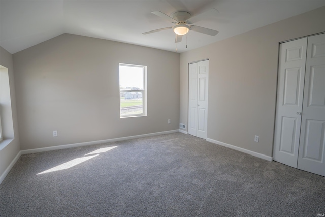 unfurnished bedroom featuring baseboards, carpet floors, lofted ceiling, and two closets