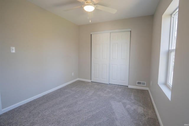 unfurnished bedroom featuring carpet flooring, a closet, a ceiling fan, visible vents, and baseboards