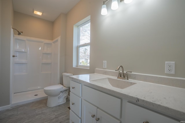 bathroom with toilet, walk in shower, vanity, and wood finished floors