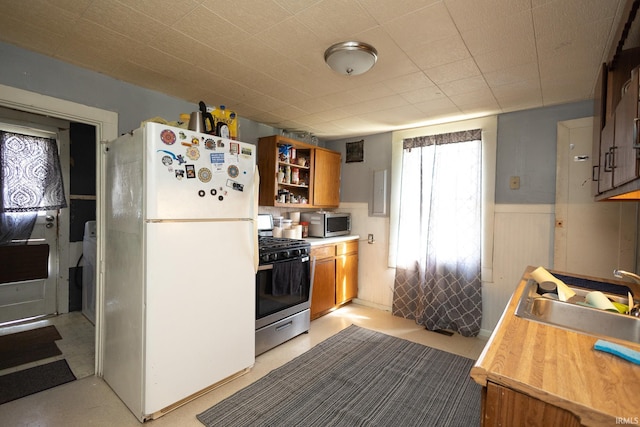 121 E Water St, Linden, IN 47955 - kitchen featuring brown cabinetry, stainless steel appliances, light countertops, a wainscoted wall, and a sink