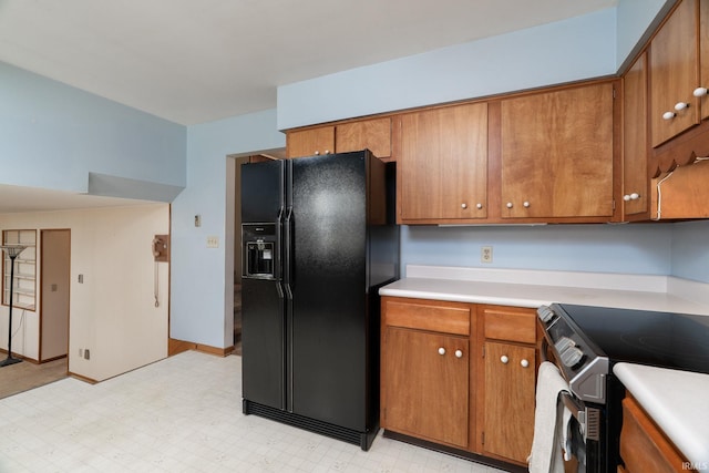 kitchen with brown cabinets, light countertops, black fridge, and stainless steel electric range