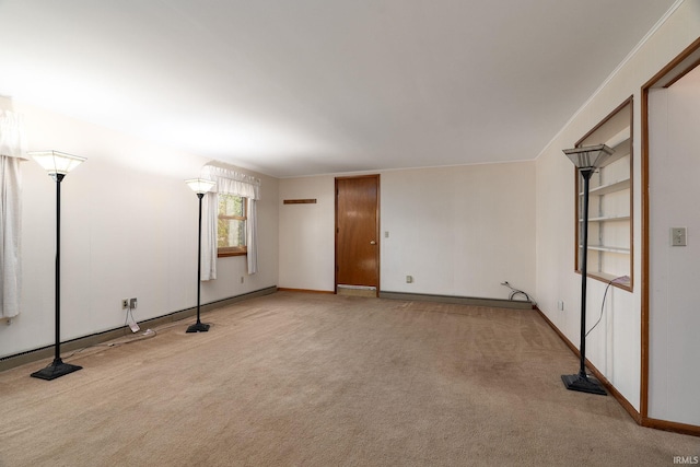 empty room featuring light carpet and baseboards
