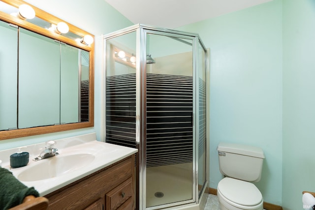 bathroom featuring toilet, a stall shower, vanity, and baseboards