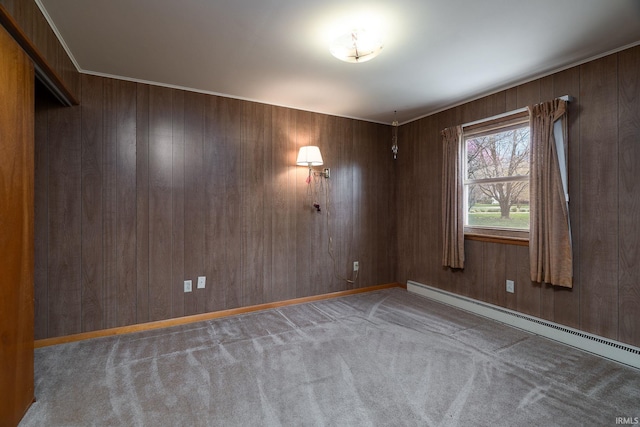 unfurnished room featuring baseboard heating, wood walls, carpet, and baseboards