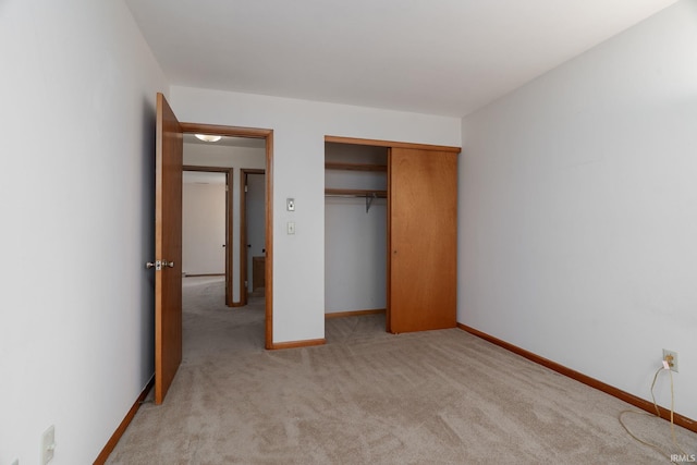 unfurnished bedroom with a closet, light carpet, and baseboards