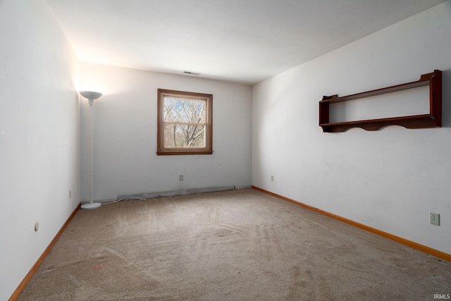 spare room featuring baseboards, visible vents, and carpet
